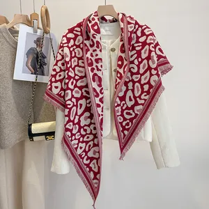 Dettaglio di una sciarpa rossa con stampa leopardata e frange su giacca di tweed