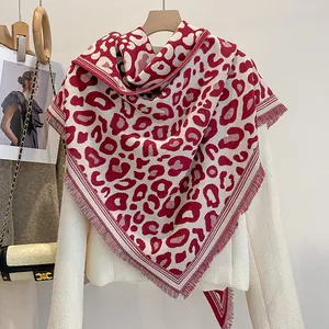 Dettaglio dello scialle leopardato bordeaux con frange su morbida maglia beige