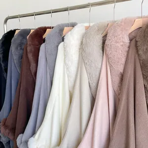Row of colorful winter capes with thick faux fur collars hanging on metal racks