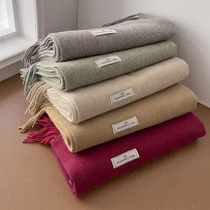 Detailed close-up of wool scarves in grey and green with fringes and textile labels