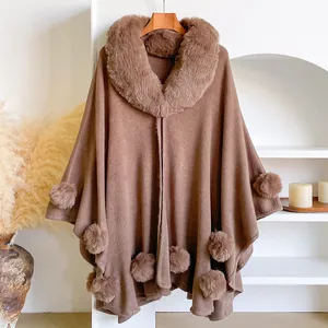 Detail of brown knitted shawl with faux fur collar and decorative pom-pom fringe