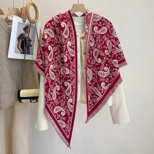 Detail of burgundy paisley scarf with tassels layered over a white tweed jacket
