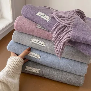 Detail of wool blend scarves in pastel colors with soft fringe and logo tags