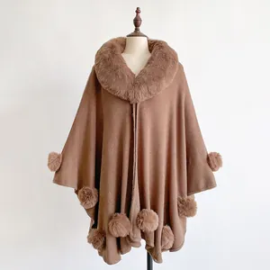 Detail of brown knit poncho with plush faux rabbit fur collar and decorative pom-poms