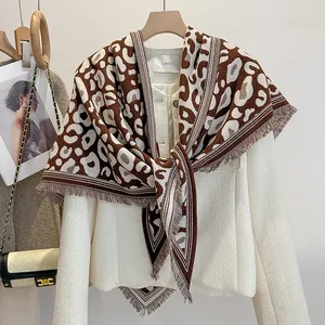 Dettaglio di scialle invernale leopardato con nappe su una giacca in tweed bianca