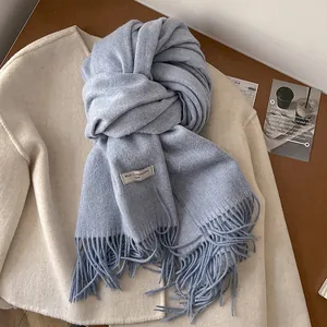 Macro detail of soft light blue wool scarf featuring elegant fringe and woven logo label