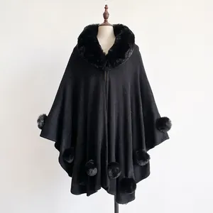 Detail of black faux fur collar and pom-poms on the loose knit cape jacket for women