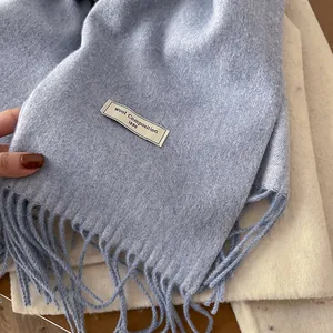 Detail of light blue wool scarf showing soft texture, tassel edges, and vintage woven label