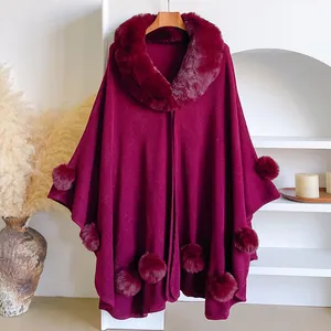 Macro detail of wine red shawl with faux rabbit fur collar and decorative pom-poms