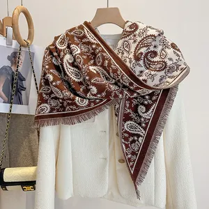 Detail of coffee brown paisley fringe scarf paired with a stylish white jacket and bag