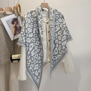 Dettaglio di scialle in maglia leopardata grigia con frange su giacca in tweed