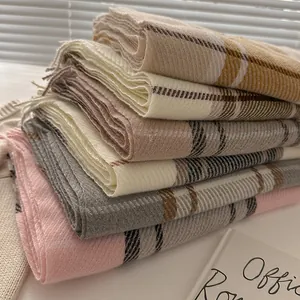 Detail showing diagonal stack of multi-color plaid wool blend scarves with fringed edges