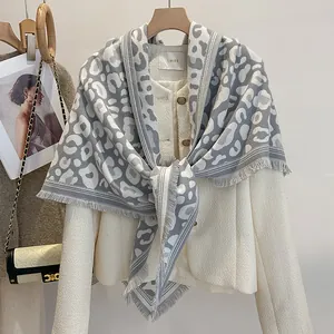 Dettaglio della sciarpa invernale leopardata grigia con nappe su giacca in tweed