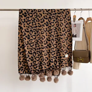Détail d'une écharpe d'hiver léopard avec des pompons en peluche décoratifs sur le bord