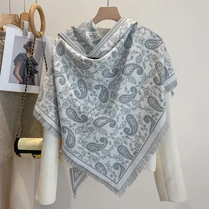 Detail of paisley pattern triangle belt with tassels styled over a tweed jacket