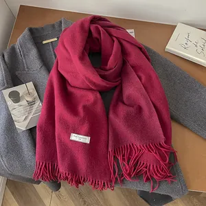 Detail of 100% wool scarf in deep pink featuring soft fabric texture and long fringe