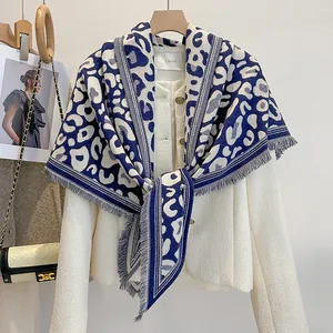 Dettaglio dello scialle leopardato bianco e blu con frange e giacca in tweed testurizzata
