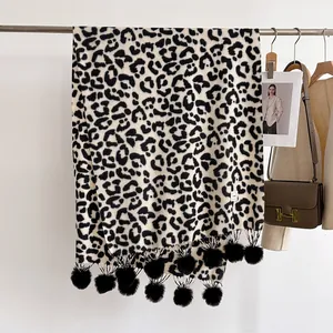 Détail d'une écharpe léopard d'hiver avec pompons noirs et tissu doux et épais