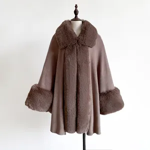 Detail of luxurious faux fur trim on deep brown knitted poncho and soft textured collar