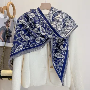 Detail view of navy blue paisley triangle belt scarf with fringe over a white tweed jacket