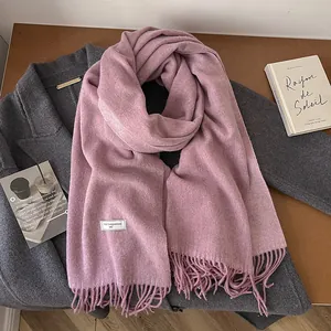 Detailed macro of dusty rose wool scarf texture with long tassels and fabric label