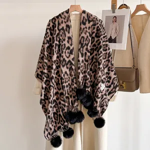 Détail de l'écharpe léopard avec pompons noirs associée à un manteau en laine beige