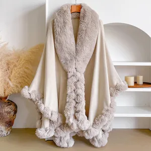 Detail of soft cream-colored knit poncho with luxurious faux fur trim and cozy texture
