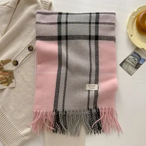 Macro detail of soft wool blend plaid scarf featuring pink tassels and brand label