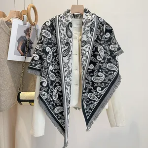 Detail of black and white paisley triangle scarf with delicate tassel trim and soft texture