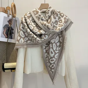 Elegante scialle invernale leopardato con frange drappeggiato su cappotto in tweed