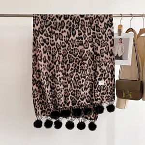 Détail d'une écharpe léopard en cachemire synthétique avec des pompons noirs élégants