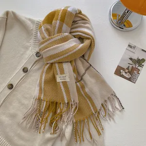 Detailed close-up of yellow and beige plaid wool scarf with fringes and brand label