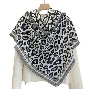 Elegante scialle invernale leopardato bianco e nero con frange su sfondo bianco
