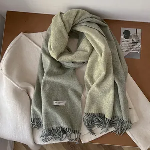 Detailed macro view of 100% sage green wool scarf fabric with delicate fringe and soft texture