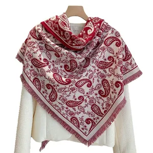 Red paisley triangle belt wrap with fringe trim over a white tweed jacket on a wooden hanger
