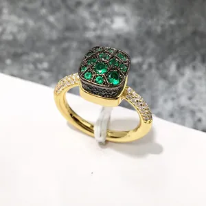 Detalle de anillo bañado en oro con piedras verde esmeralda y circonitas blancas finas