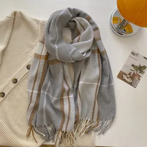 Close-up of gray and coffee plaid wool scarf with delicate fringe on soft knitwear