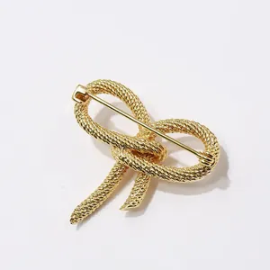 Detail of golden bow brooch showing intricate braided rope texture and metal pin back