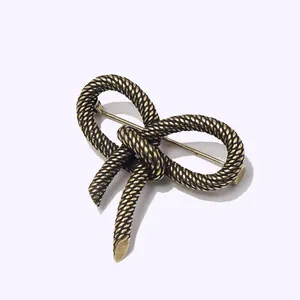 Elegant vintage brass bowknot brooch with twisted rope texture on a white background