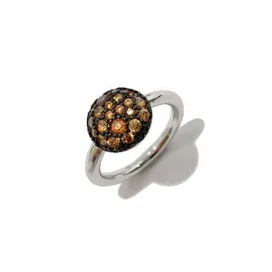 Gros plan d'une bague argentée avec surface bombée ornée de cristaux pavés marrons
