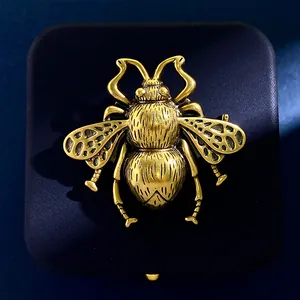 Vintage gold bee brooch with textured wings on a premium dark velvet background