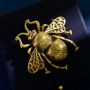 Close-up of vintage bee brooch with intricate hollow-carved wings on navy gift box