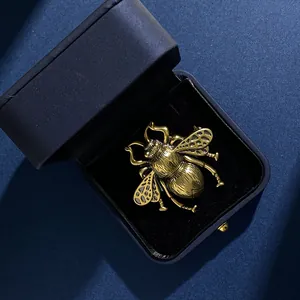 Macro detail of a vintage golden bee brooch with hollow wings in a luxury blue jewelry box