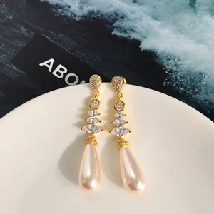 Dettaglio di orecchini lunghi placcati in oro con zirconi marquise e perle champagne a goccia