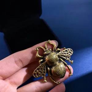 Macro detail of a vintage gold bee brooch with textured wings shown on fingertips