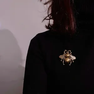 Vintage golden bee brooch with honeycomb wing textures on a black sweater