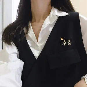 Detail of gold letter R and G pendants with bamboo texture on a safety pin brooch