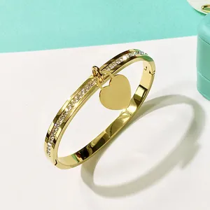 Bracciale rigido dorato con ciondolo a cuore lucido e pavé di diamanti brillanti