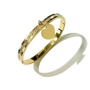 Bracciale rigido dorato lucido con ciondolo a cuore, cristalli scintillanti e chiusura a scatto