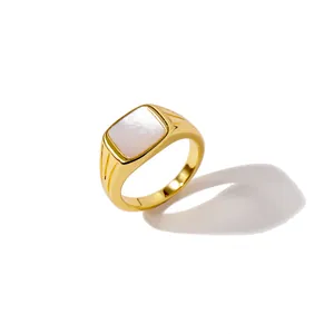 Bague minimaliste en laiton doré avec nacre carrée blanche sur fond blanc immaculé